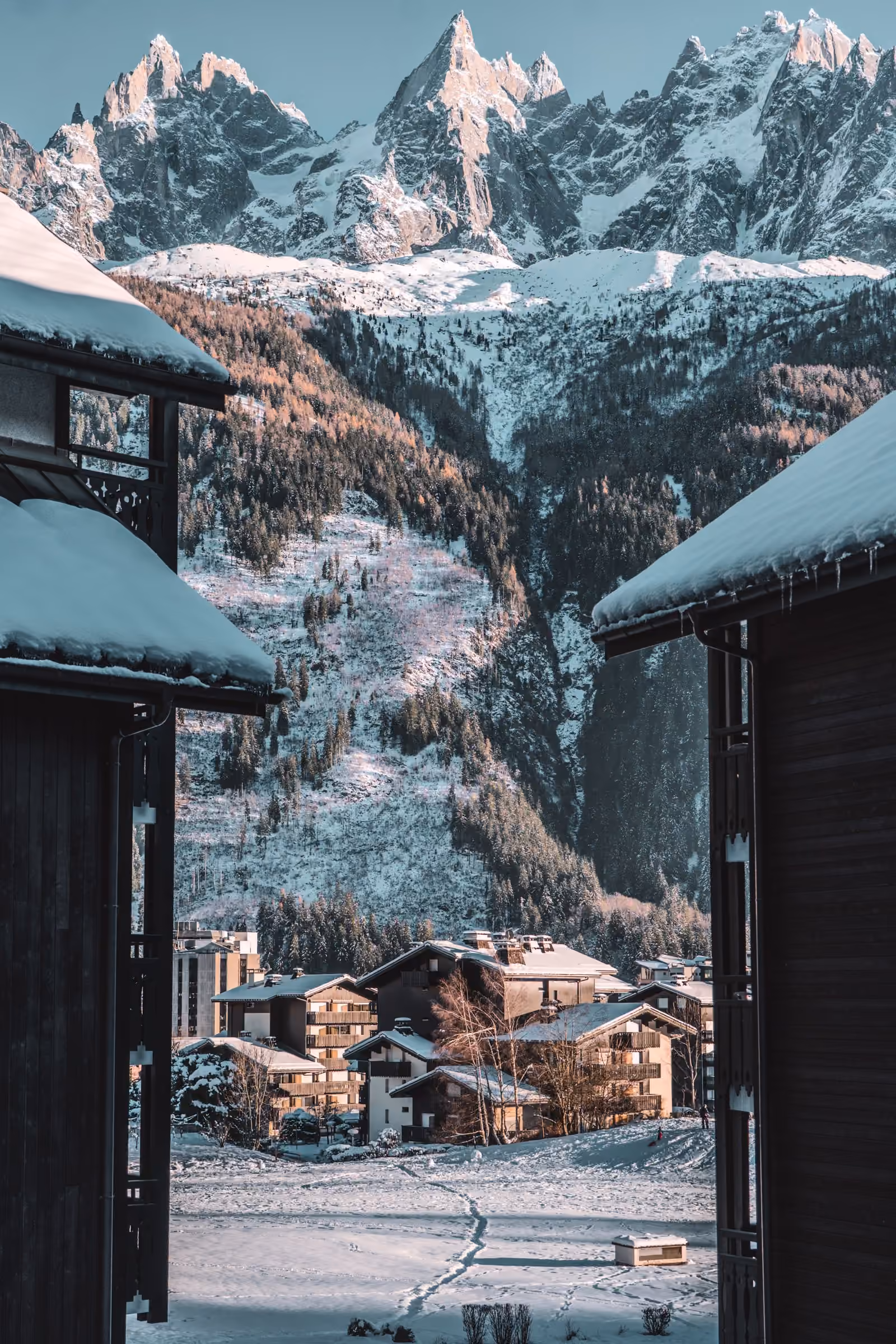 Chalets enneigés au pied d’aiguilles granitiques dans les Alpes françaises.