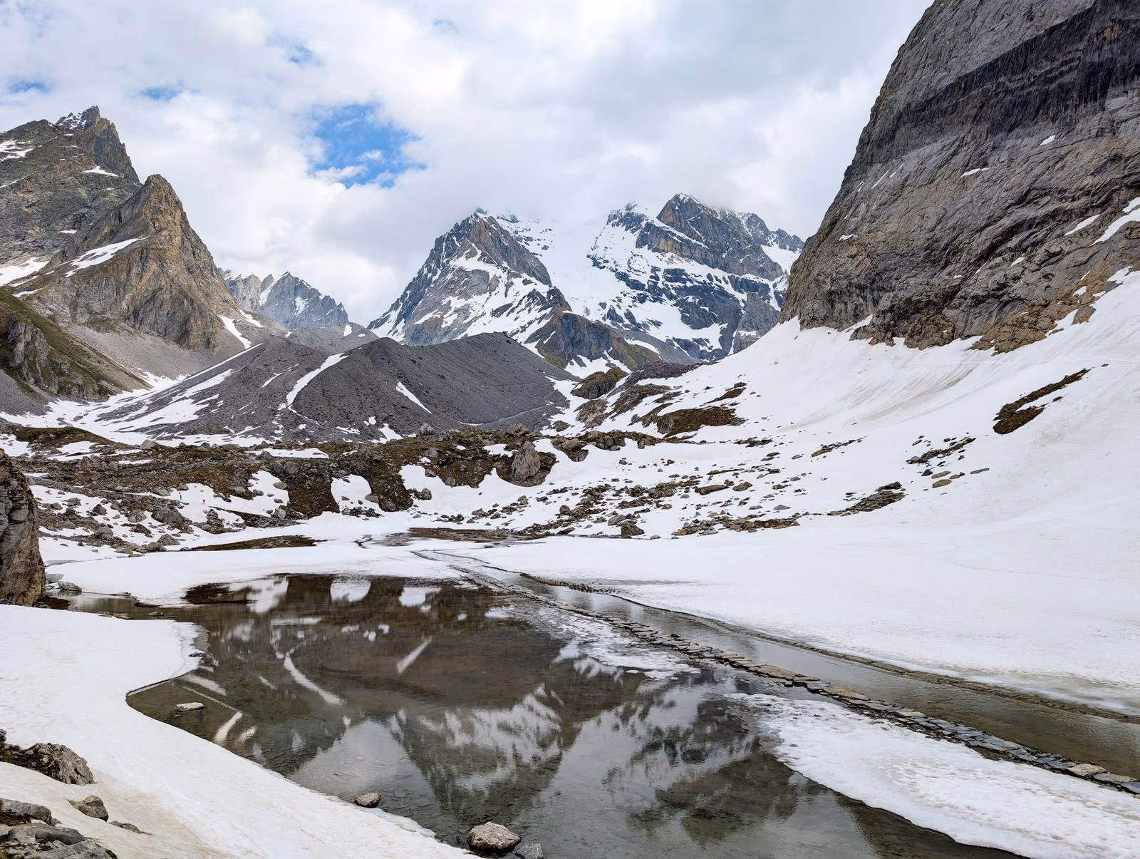 Sommets enneigés se reflétant dans un lac alpin immobile.