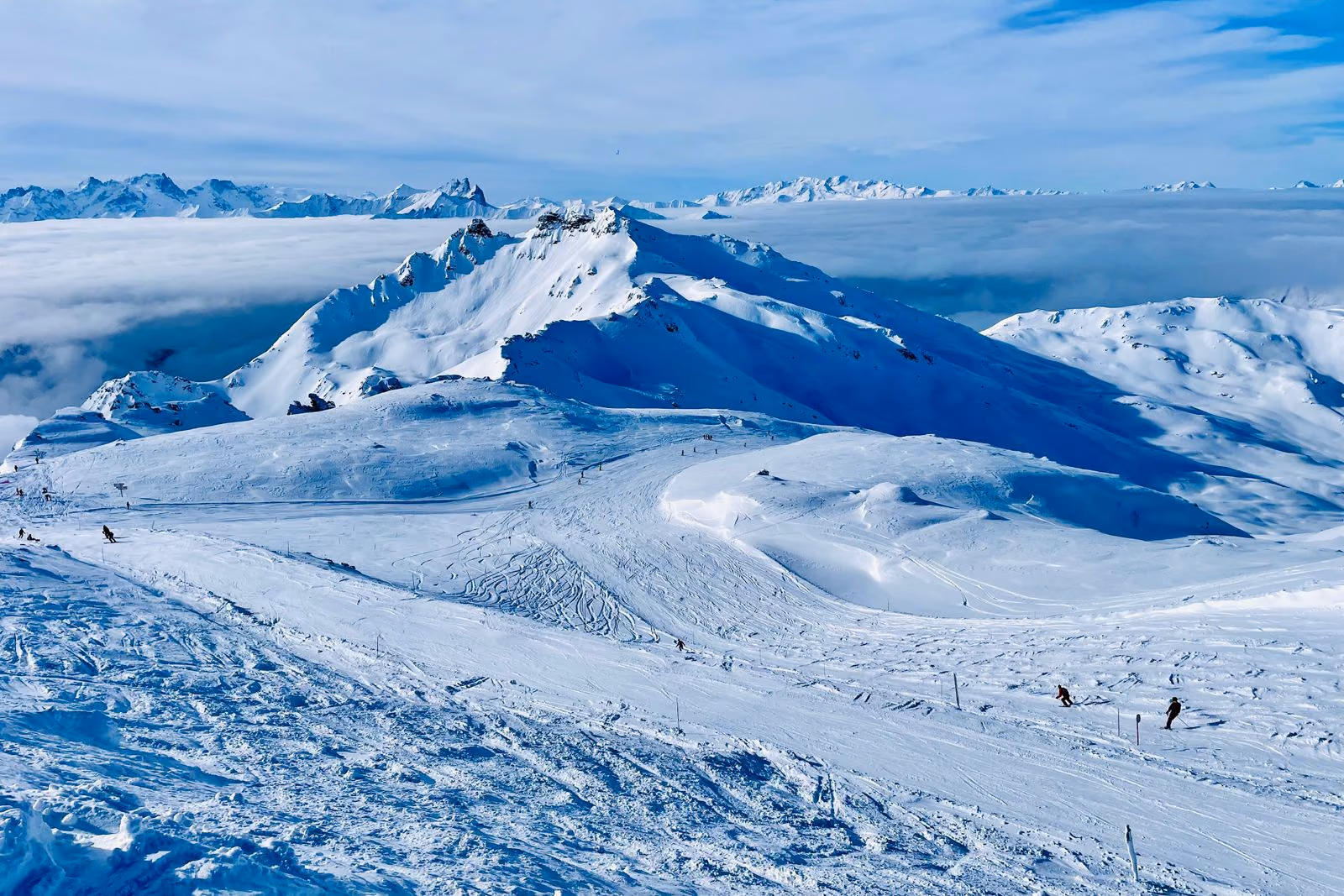 Une station de ski de montagne enneigée en hiver, sous un ciel dégagé.